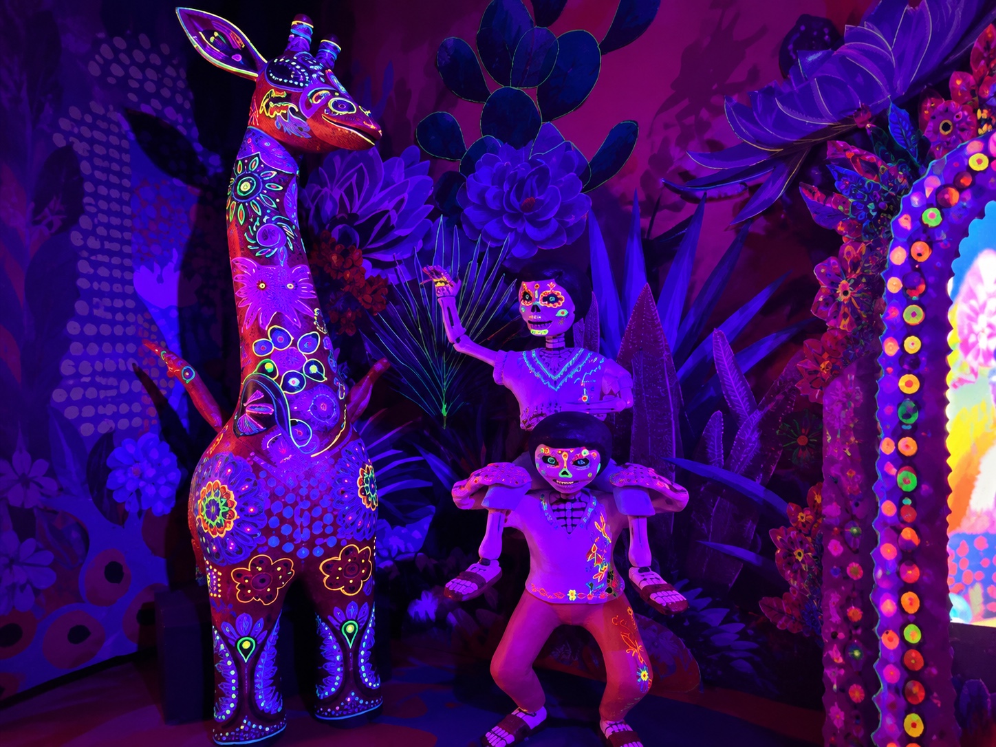 Fluorescent alebrije giraffe and colorful skeleton figures inside Colors of Mexico