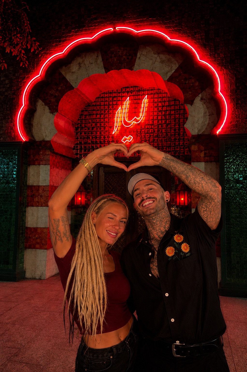 Lana and Kyle making a heart beneath the red neon entrance at Leila in North Park